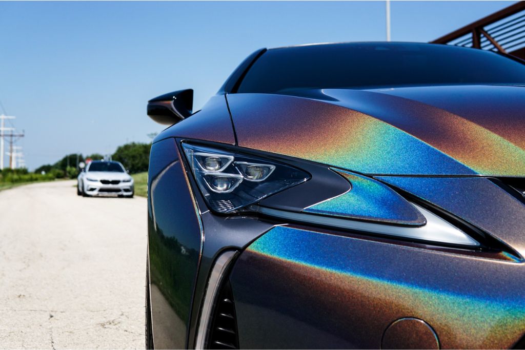 Close-up of the front end of a luxury car with a striking iridescent paint job, enhanced and protected by Paint Protection Film. The PPF maintains the vibrant, reflective finish while shielding against environmental hazards like UV rays and acid rain.