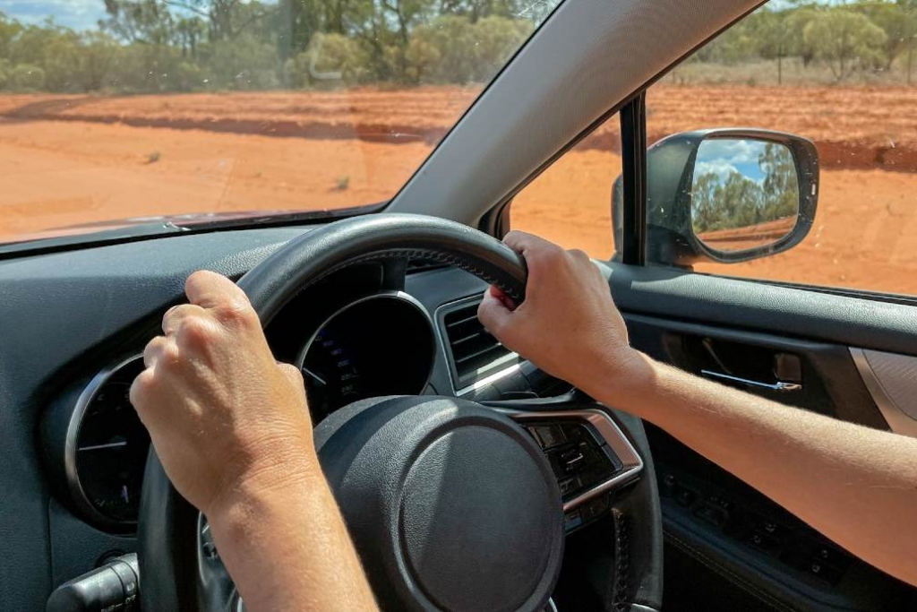 Driver's hands on the steering wheel of a sunlit vehicle interior, with visible sunlight streaming through untinted windows, highlighting the benefits of window tinting for reducing solar heat and improving thermal comfort in variable climates like Illinois.