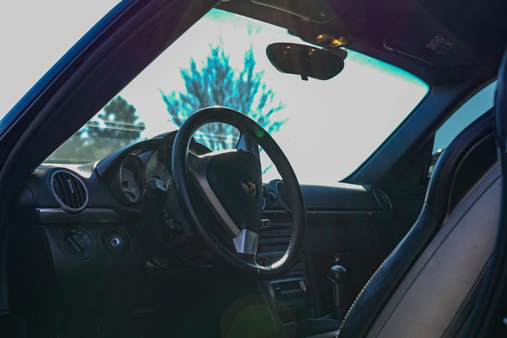 Sunlight shining into a clean, well-maintained car interior with leather seats and intact dashboard, illustrating the benefits of window tinting in preserving interior materials and maintaining resale value over time.