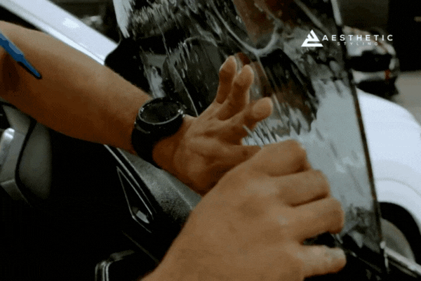 Close-up of a technician from Aesthetic Styling in Naperville, Illinois, expertly applying XPEL window film to a car door using a squeegee and precision technique, highlighting their trusted reputation for high-quality window tinting services.